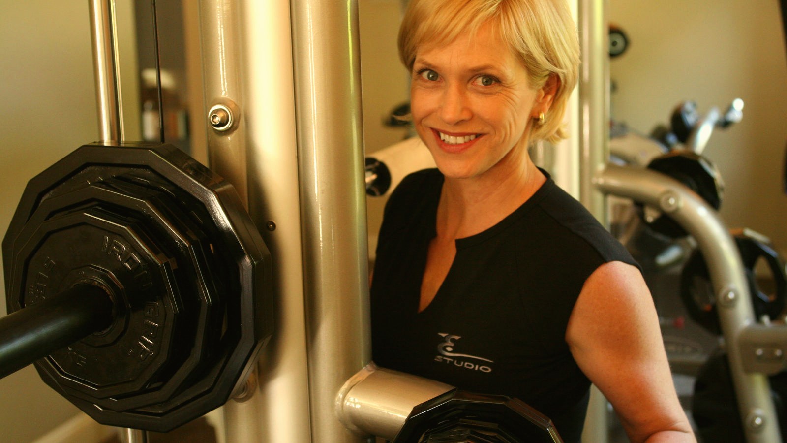 A trainer demonstrates correct form on a strength machine.